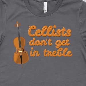 May include: A charcoal grey t-shirt with the text "Cellists don't get in treble" in orange lettering. A cello is pictured in the top left corner of the shirt.