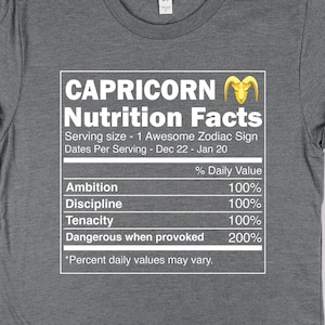 May include: Gray t-shirt with a nutrition facts label for Capricorn. The label lists the daily value of ambition, discipline, tenacity, and dangerous when provoked. The text "Capricorn Nutrition Facts" is in a bold, yellow font.
