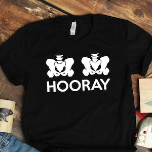 May include: Black t-shirt with a white graphic of two skeletons with the word "HOORAY" underneath.