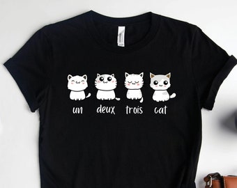 May include: Black t-shirt with a graphic of four white cats and the text "un deux trois cat".