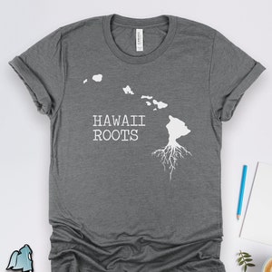 Könnte beinhalten: Graues T-Shirt mit einem weißen Umriss der hawaiianischen Inseln und dem Text "HAWAII ROOTS".