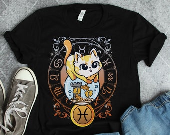 Pode incluir: Camiseta preta com um gráfico de um gato em um aquário com o símbolo do zodíaco de Peixes. O gato é amarelo e branco com marcas laranja. O aquário é cercado por uma moldura decorativa com os símbolos do zodíaco de Câncer, Touro, Gêmeos e Aquário.