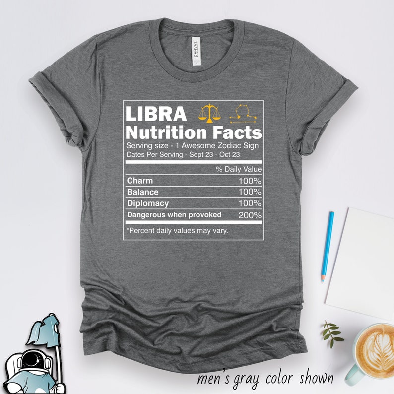 Pu&ograve; includere: Maglietta grigia con una grafica bianca di un'etichetta di informazioni nutrizionali per la Bilancia, un segno zodiacale. La grafica include il simbolo della Bilancia e le date dal 23 settembre al 23 ottobre. L'etichetta elenca quanto segue: Fascino, Equilibrio, Diplomazia e Pericoloso quando provocato, tutti con un valore giornaliero del 100% tranne Pericoloso quando provocato, che ha un valore giornaliero del 200%.