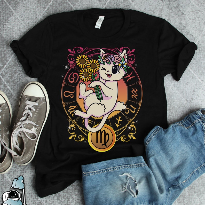 May include: Black t-shirt with a white cat wearing a flower crown and holding a bouquet of sunflowers. The cat is surrounded by a gold zodiac symbol for Virgo.
