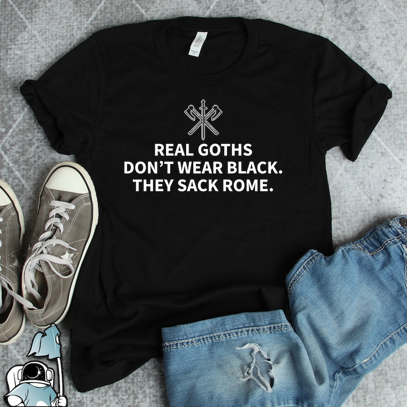 May include: Black t-shirt with white text that reads "REAL GOTHs DON'T WEAR BLACK. THEY SACK ROME."  The shirt features a graphic of two crossed swords with axes.