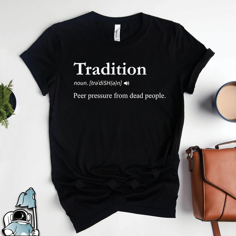 May include: Black t-shirt with white text that reads "Tradition" and a definition of the word as "peer pressure from dead people."