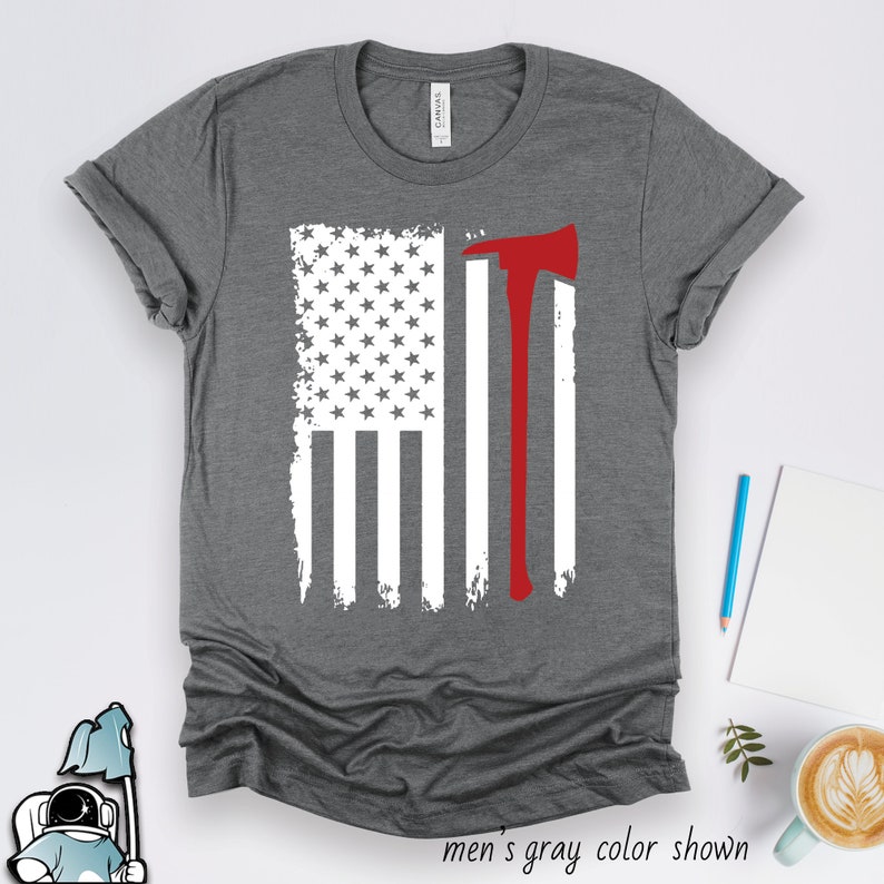 May include: A gray t-shirt with a white and red American flag design. The flag has an axe in the right side of the flag. The text 'men's gray color shown' is below the image.