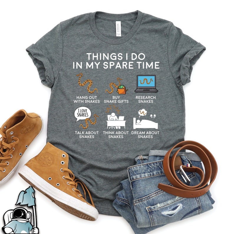 Puede incluir: Una camiseta gris con el texto "Things I do in my spare time" e ilustraciones de serpientes. Las ilustraciones incluyen pasar tiempo con serpientes, comprar regalos de serpientes, investigar serpientes, hablar de serpientes, pensar en serpientes y so&ntilde;ar con serpientes.