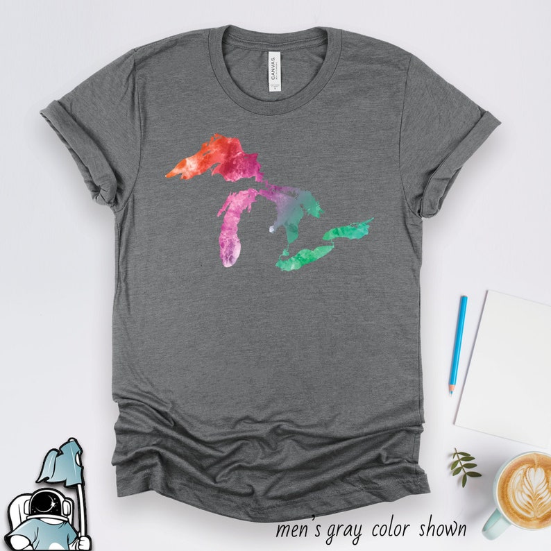 May include: A heather gray t-shirt with a watercolor design of the Great Lakes in shades of pink, orange, green, and blue. "men's gray color shown" is written below the image.