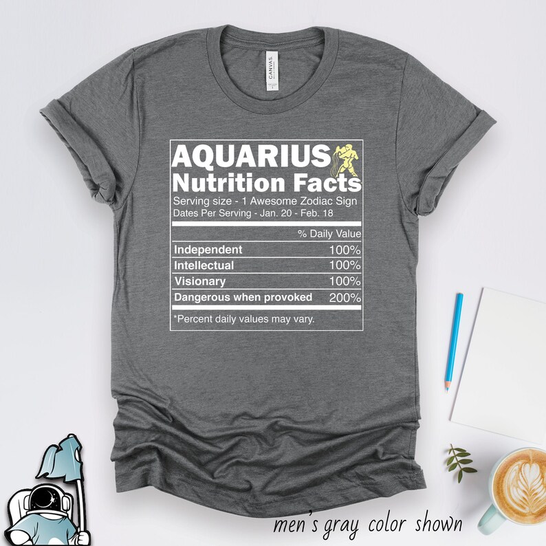 May include: Gray t-shirt with a white graphic of a nutrition facts label for Aquarius. The label lists traits like "Independent", "Intellectual", "Visionary", and "Dangerous when provoked" with a percentage value of 100% or 200%.