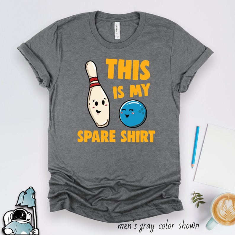 Puede incluir: Camiseta gris con un gr&aacute;fico de un pin de bolos y una bola de bolos. El texto de la camiseta dice "This is my spare shirt."