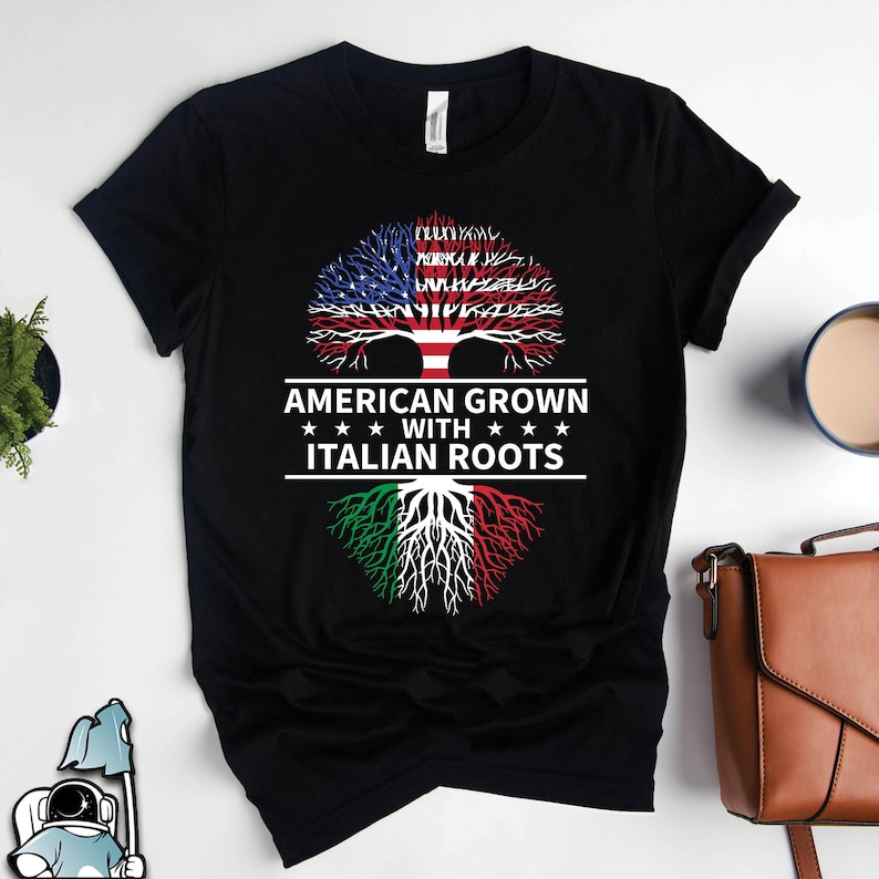 May include: Black t-shirt with a tree design. The tree has American flag leaves and Italian flag roots. The text reads "American Grown with Italian Roots".