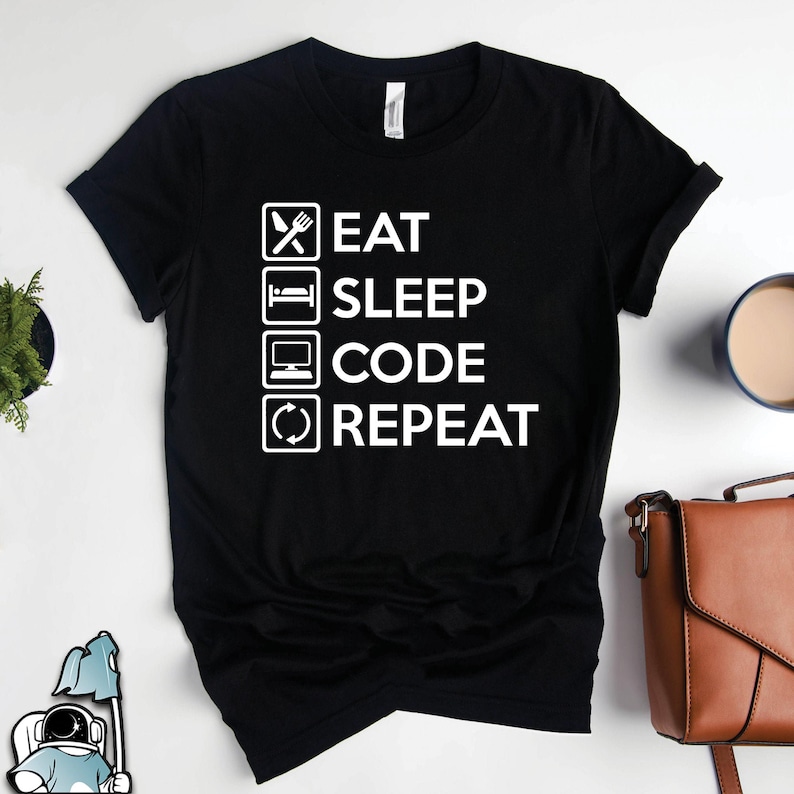 May include: A black t-shirt with white text that reads 'Eat Sleep Code Repeat' in a checklist format with checkmarks next to each item.