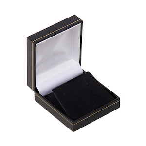 May include: A black jewellery box with a gold trim and a black velvet interior. The box is open and the lid is propped up.