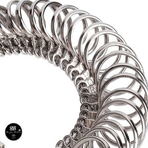 May include: A set of silver ring sizers, arranged in a circle, for measuring finger size.