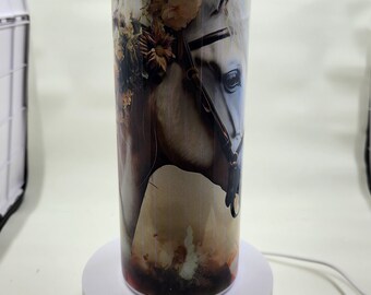May include: White stainless steel tumbler with a floral design and a horse's head with a bridle. The tumbler is on a white rotating display stand.