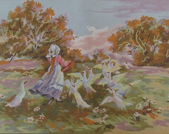 May include: A girl in a pink and white dress walks through a field with a flock of white geese. The geese are in a line, following the girl. The background is a field with trees and a blue sky.