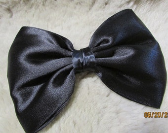 May include: A large black satin bow. The bow is made of a soft, smooth fabric and has a classic, elegant design.
