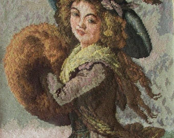 May include: A needlepoint tapestry depicting a woman in a blue hat with a brown feather, holding a brown fur muff. The woman is wearing a green and brown dress and a white scarf. The background is a light gray with a landscape in the bottom left corner.