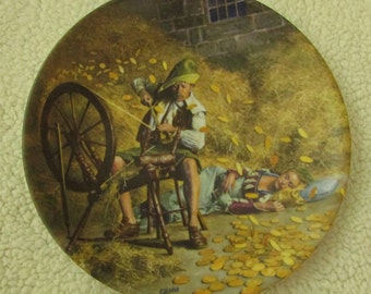 May include: A vintage ceramic plate depicting a scene from the fairy tale Rumpelstiltskin. A man spins a wheel while a woman sleeps surrounded by gold coins.