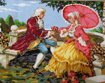 May include: A needlepoint tapestry depicting a couple in 18th-century clothing. The man is wearing a red coat and the woman is wearing a yellow and pink dress with a pink parasol. They are standing in a garden setting with flowers and trees.