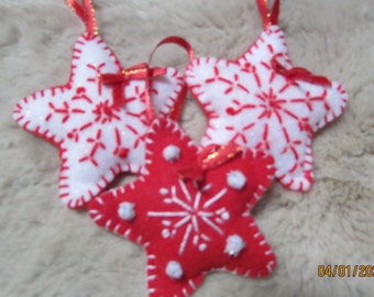 May include: Three felt star ornaments with white snowflake designs. Two stars are white with red stitching and one star is red with white stitching.