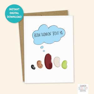 May include: A white card with a blue thought bubble that says "Bean thinkin' 'bout ya".  There are five beans in a row below the thought bubble: a black bean, a brown bean, a red bean, a white bean, and a green bean.