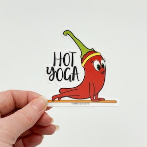May include: A red chili pepper cartoon character doing a yoga pose on a white yoga mat. The text "HOT YOGA" is written in black above the chili pepper.
