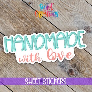 May include: A white sticker with the words "HANDMADE with love" in teal and coral lettering. The sticker is on a wooden surface, with the words "SHEET STICKERS" in white on a purple banner below.