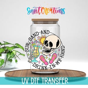 a glass jar with a skull and beach-themed design, along with the text "SUN-SAND-AND DRINK-IN MY HAND" and "UV DFT TRANSFER".