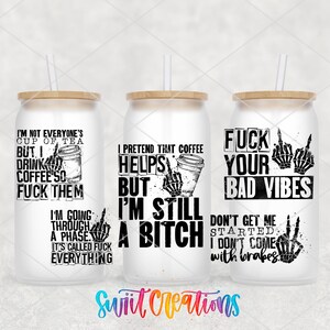 three white tumblers with black text and graphics printed on them. The text and graphics include phrases such as "I'm not everyone's cup of tea but I drink coffee so I'm going through a phase it's called fuck everything", "I pretend that coffee helps me but I'm still a witch", and "FUCK YOUR BAD VIBES".