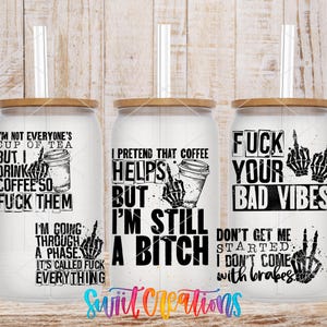 three white tumblers with black text and graphics printed on them. The text appears to be a humorous and edgy take on coffee culture, with phrases such as "I'm not everyone's cup of tea", "Drink coffee so I can fuck them", "I pretend that coffee helps me through a phase", "I'm still a shit", and "FUCK YOUR BAD VIBES". The tumblers are displayed against a wooden background, which adds to the overall edgy and unconventional aesthetic of the image.
