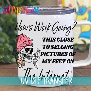 A white mug with a skeleton wearing a pink beanie and holding a drink, along with text that says "How's Work Going? This Close to Selling Pictures of My Feet on the Internet".