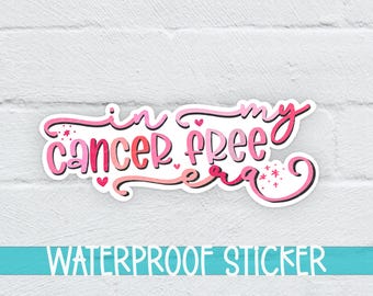 Peut inclure: Autocollant imperméable rose et blanc avec le texte "in my cancer free era" dans une police d'écriture manuscrite. L'autocollant a des cœurs et des étoiles roses.