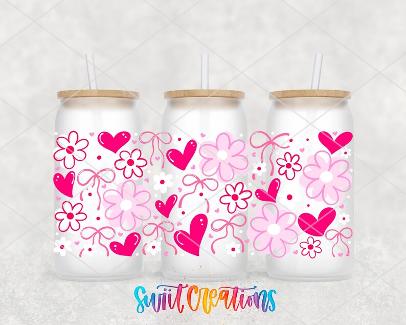three frosted glass tumblers with pink and white floral designs, including hearts and flowers, along with straws.