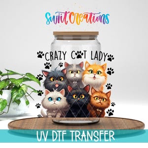May include: A glass jar with a wooden lid, decorated with a colourful illustration of six cartoon cats. The text "CRAZY CAT LADY" is displayed, along with paw prints. The words "UV DTF TRANSFER" are at the bottom.