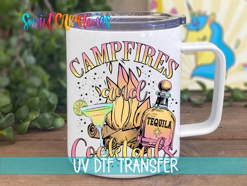 A white mug with a colorful design featuring a tequila bottle, cocktail glass, and campfire, along with the text "CAMPFIRE'S and Cocktails" and "UV DFT TRANSFER".