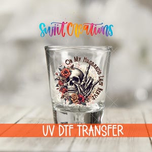 Puede incluir: Un vaso de chupito transparente con un diseño de calavera y flores. La calavera está rodeada de rosas rojas y naranjas, con una mano de esqueleto haciendo una peineta. El texto en el vaso dice "On My Husband's Last Nerve."