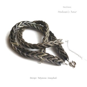 May include: A silver necklace with a braided chain design, called "Medusa's hair". The necklace is made of small, silver beads woven together to create a thick, rope-like chain. The necklace is designed by Tetyana Smeykala.