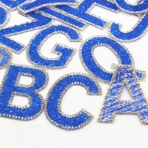 Puede incluir: Surtido de letras del alfabeto de strass azul para planchar. Las letras están hechas de plástico transparente con strass azul que cubre la superficie.