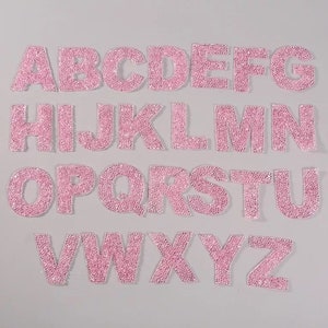 Peut inclure: Lettres de l'alphabet en strass rose. Chaque lettre est composée de petits strass roses et mesure environ 5 cm de haut.