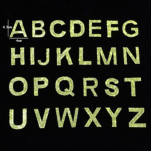 Peut inclure: Un ensemble de 26 lettres de l'alphabet en strass. Les lettres sont jaunes et sont disposées en ordre alphabétique. Chaque lettre mesure environ 4 cm de large et 4,5 cm de haut.