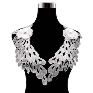 Può includere: Bordino in pizzo bianco con un motivo floreale. Il bordino presenta un motivo delicato e intricato con un bordo smerlato. È perfetto per aggiungere un tocco di eleganza a qualsiasi progetto.
