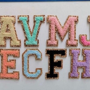 May include: A set of eight felt letters with gold glitter trim. The letters are A, V, M, J, E, C, F, and H. The letters are in various colors, including pink, light blue, light green, yellow, and purple.