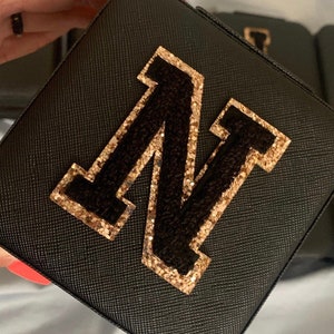 May include: Black square box with a gold glitter and black felt letter N on the front.