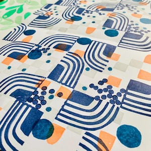 May include: A white paper sheet featuring a repeating pattern of dark blue arched lines, solid blue circles, clusters of small blue dots, and light orange semi-circles arranged in a grid-like layout with faint gray squares in the background.