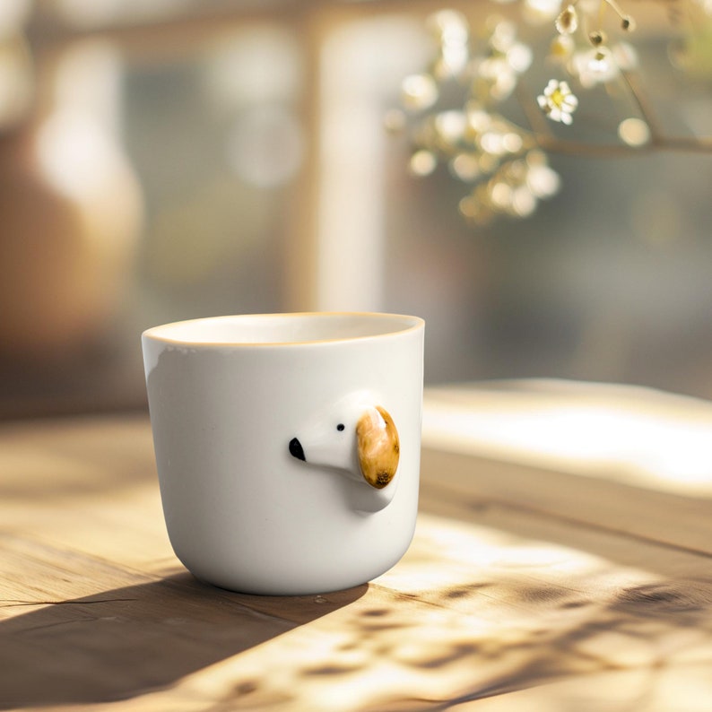 May include: White ceramic mug with a small dog's face sculpted on the side. The dog has brown ears and a black nose.