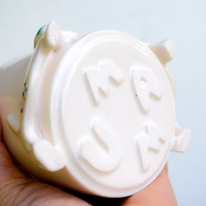 May include: White ceramic mug with the word "MAMA" embossed on the side.