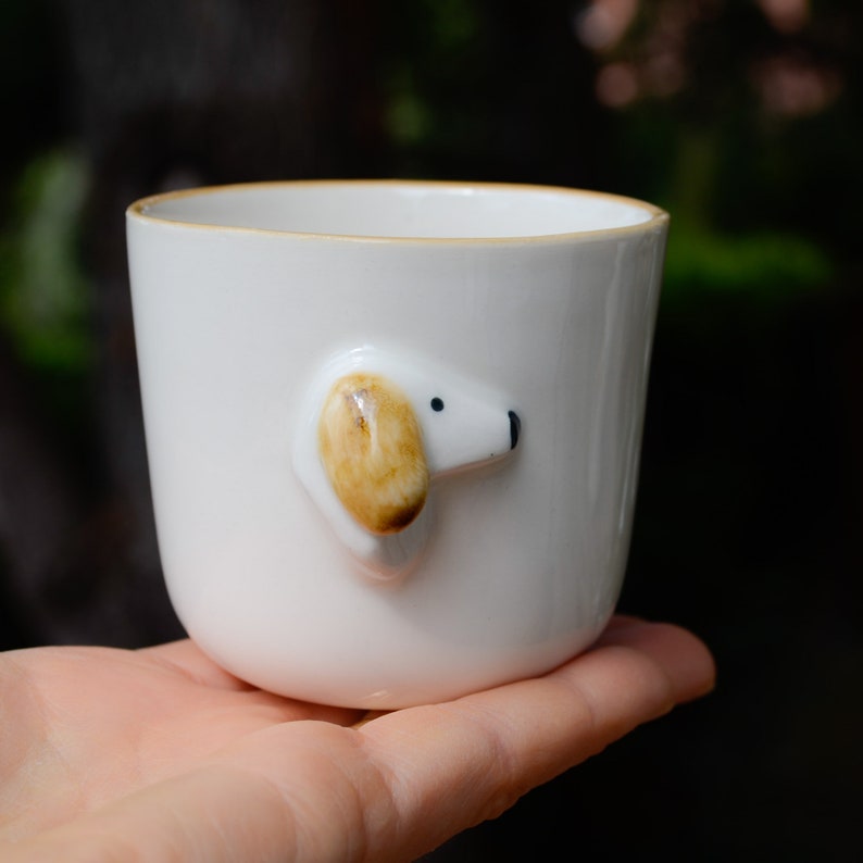 May include: White ceramic mug with a small, 3D dog face on the side. The dog has brown ears and black eyes.