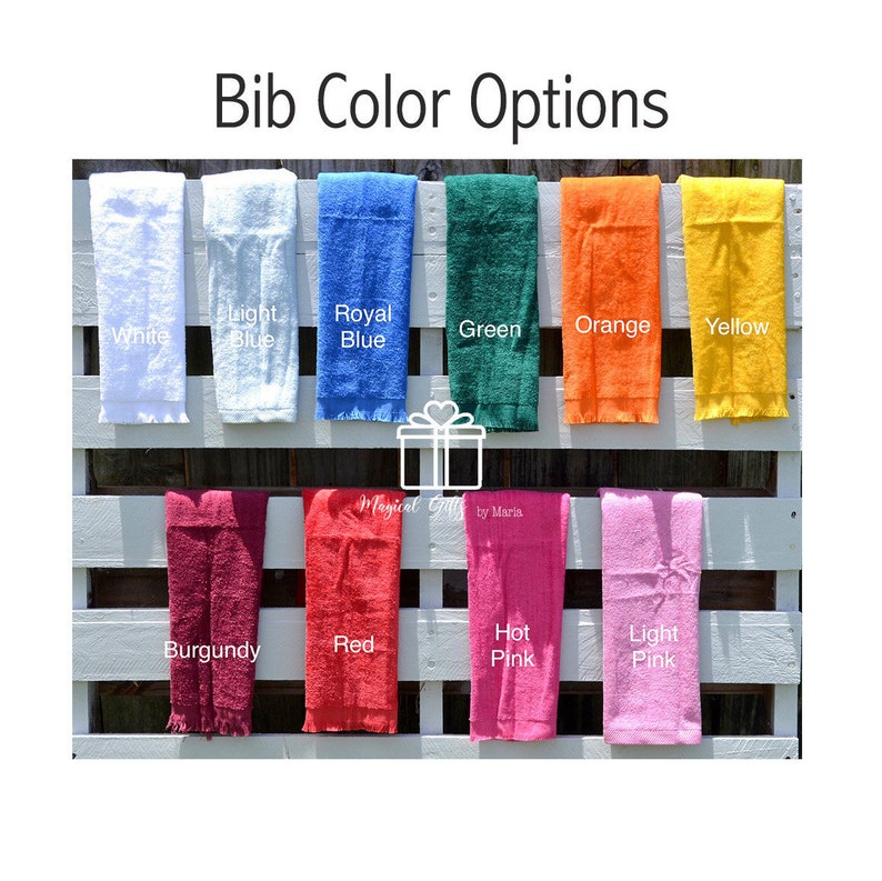 Op de afbeelding: Een selectie van 12 verschillende gekleurde handdoeken, gepresenteerd op een witte houten lattenwand. De handdoeken zijn gerangschikt in twee rijen van zes, waarbij elke handdoek is gelabeld met zijn kleur. De kleuren zijn: wit, lichtblauw, koningsblauw, groen, oranje, geel, bordeauxrood, rood, roze, lichtroze.